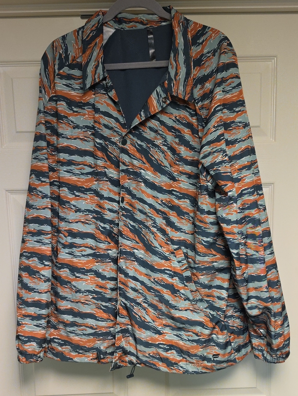 Fabletics Striped Wave Coach Jacket in Teal, Orange, and Navy